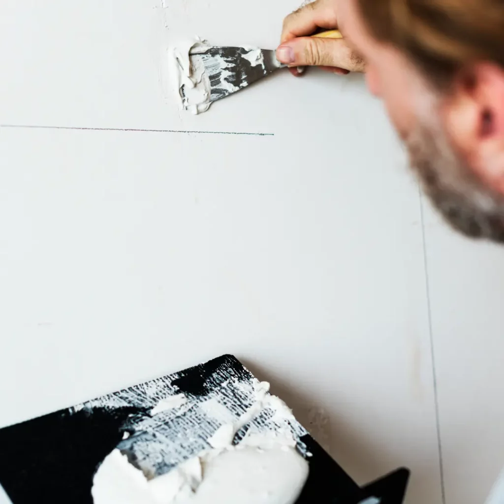 A person applying a white mixture on the board for finishing